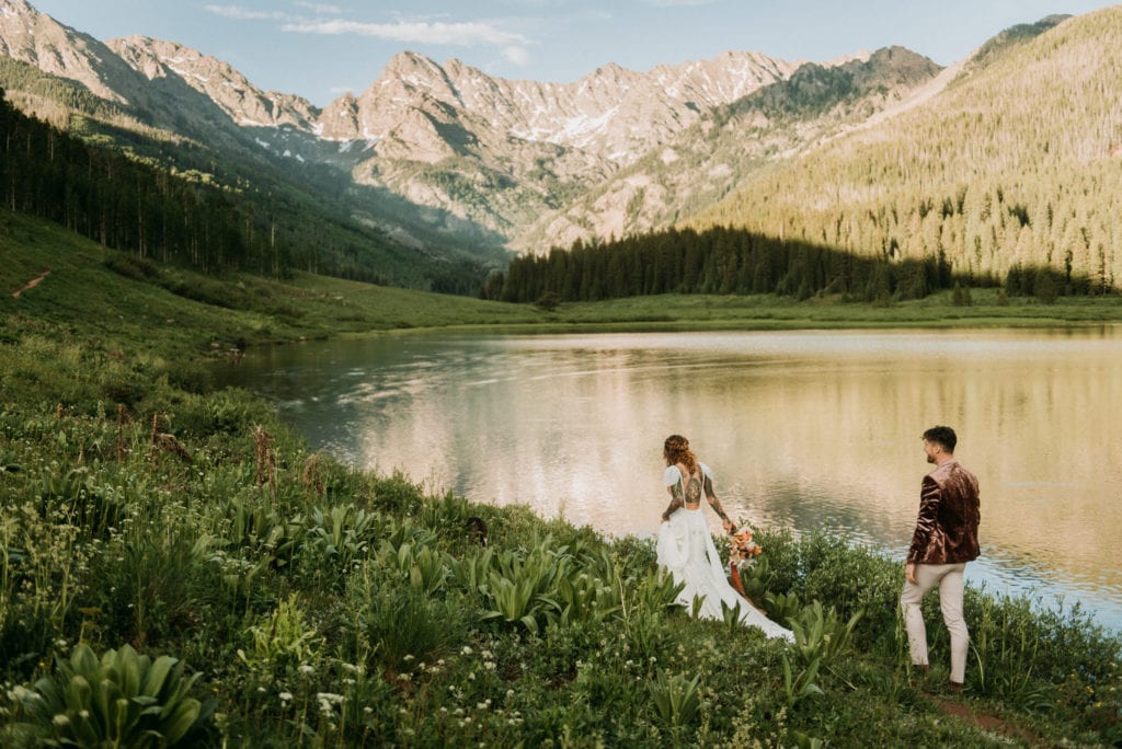bride and groom walking near lake and mountains after their national park wedding ceremomy