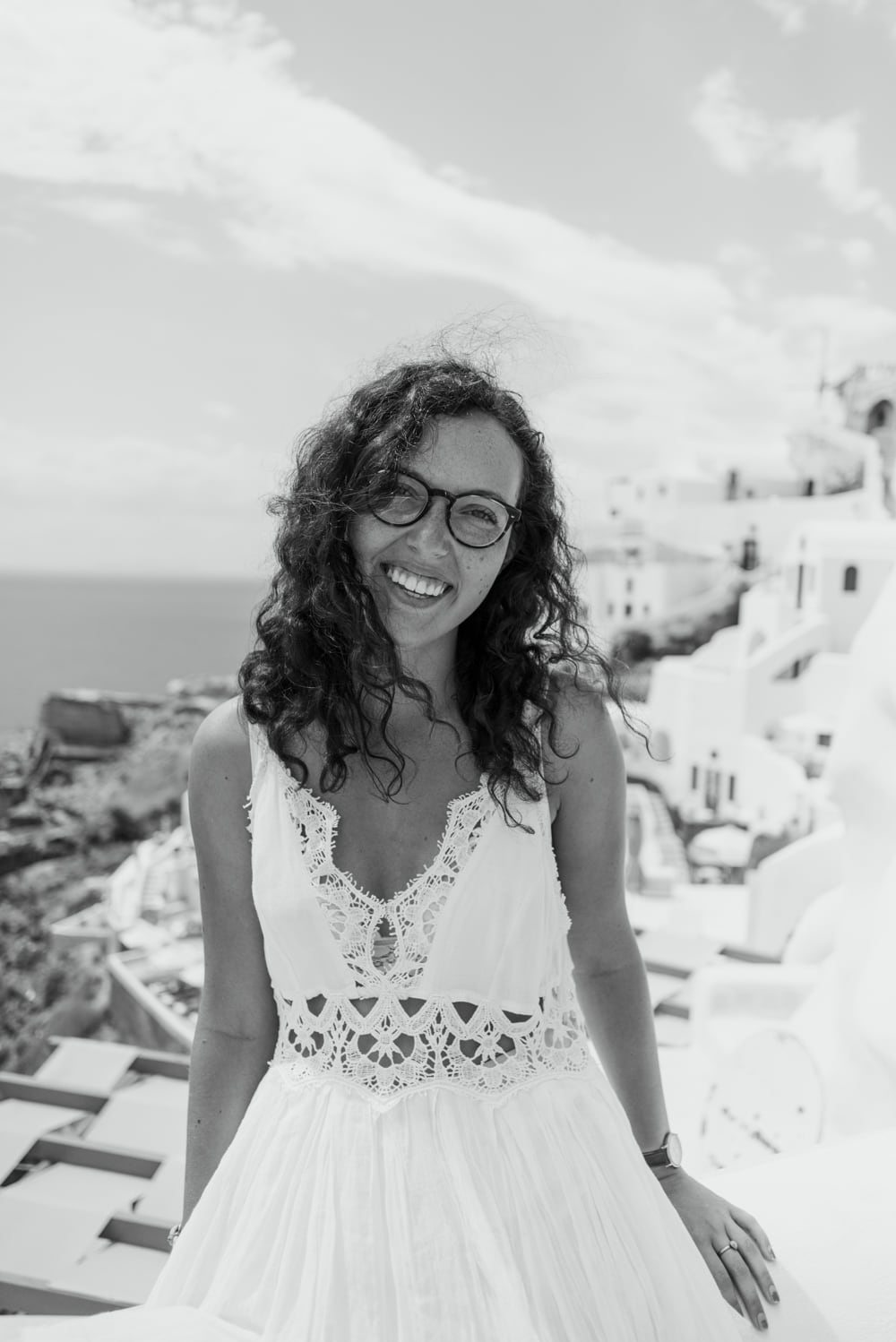 Photographer in front of the white buildings lining the coast in Santorini, Greece