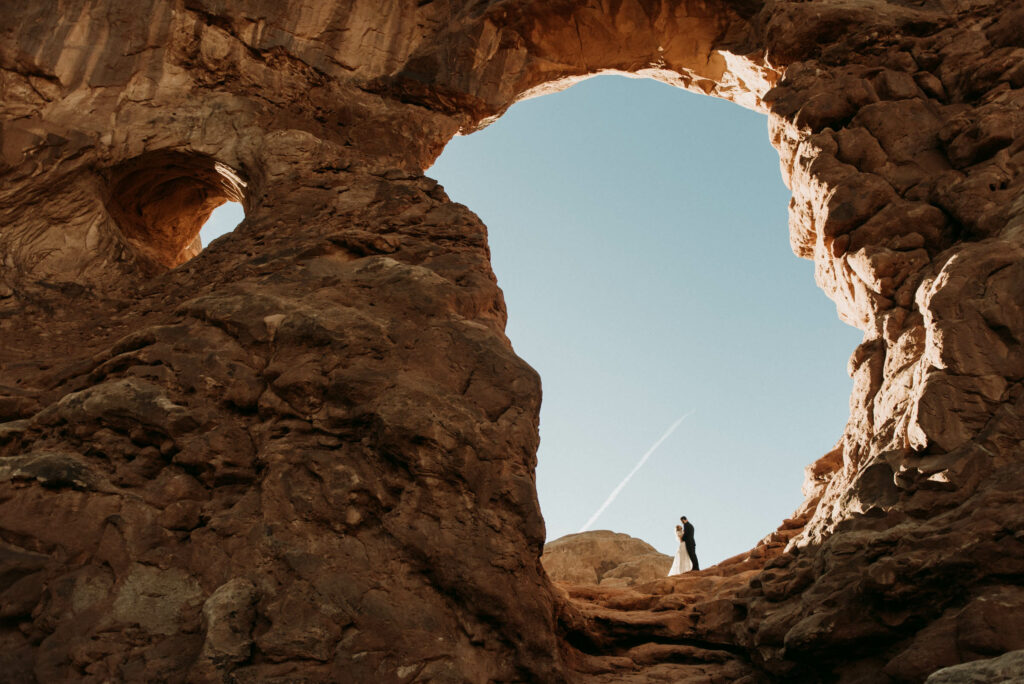A couple stands underneath Turret Arch in Arches National Park, one of my favorite elopement locations in Utah.