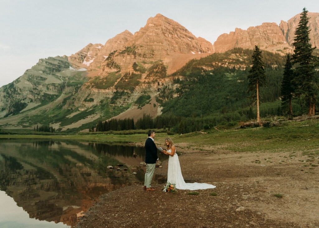 A couple having their ceremony during their sunrise hiking elopement at Maroon Bells in Aspen Colorado, a magical outdoor micro wedding venue in Colorado