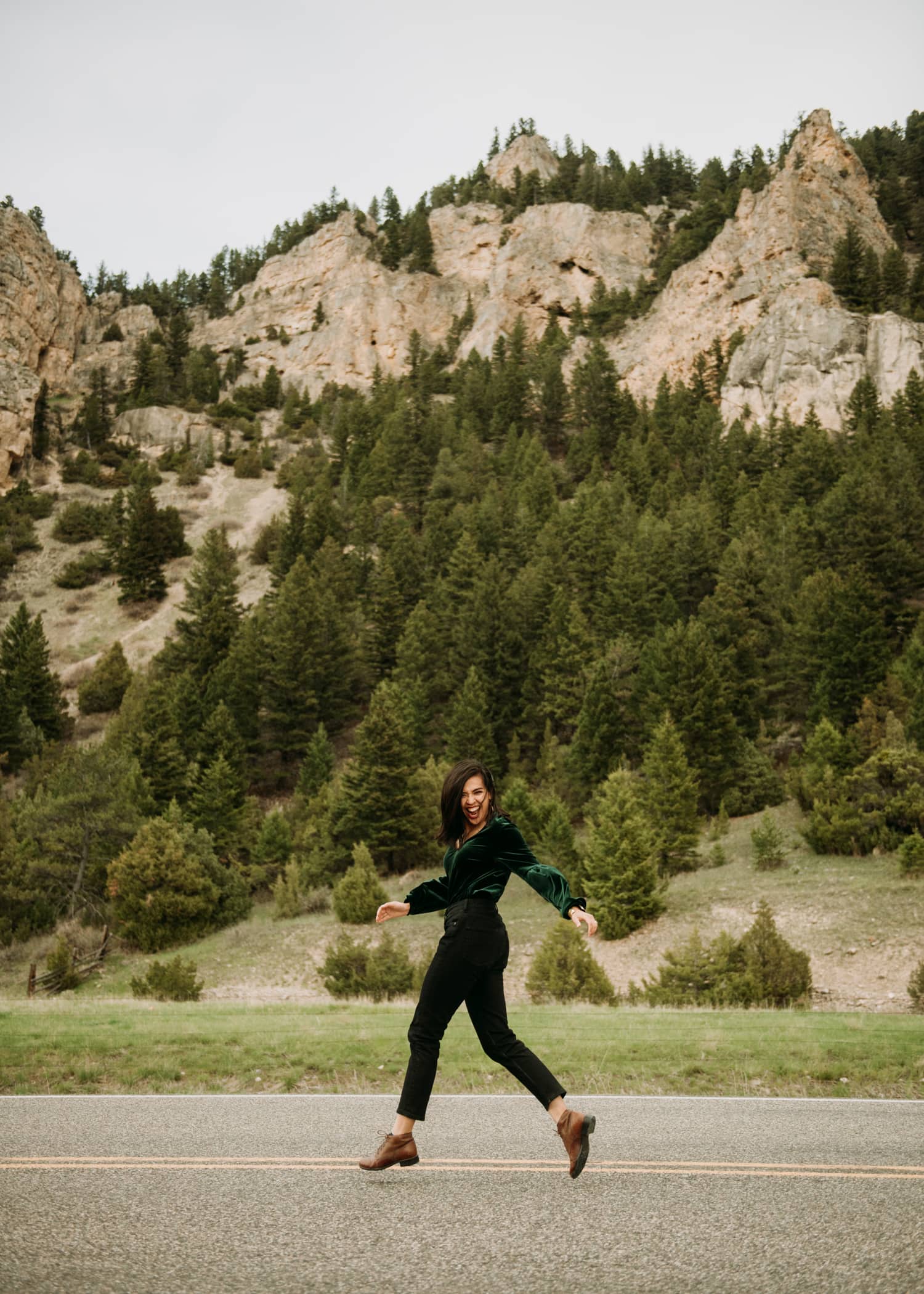 A girl running and laughing in front of mountains in Paradise Valley, Montana.