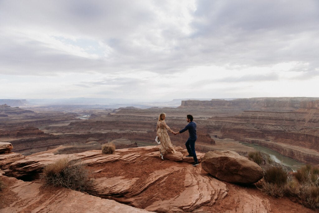 bride and groom standing on red rocks at their moab elopement