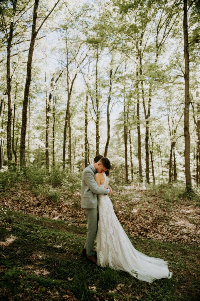 Newlyweds embracing in a forest during their first look before their intimate heartfelt ceremony in Bloomington, Indiana at the Wilds Venue.