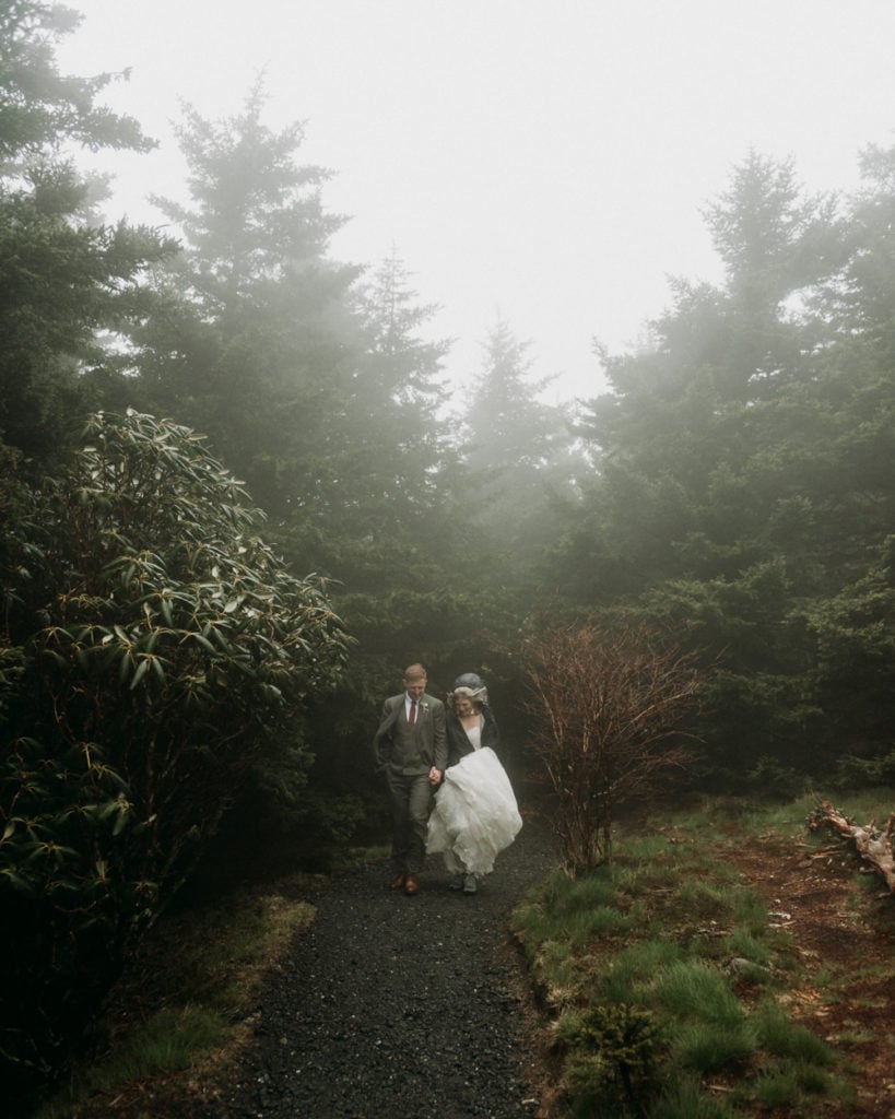 Right after their elopement ceremony, a couple walks out of the fog through the forest at Roan Mountain State Park in Tennessee, one of the best places to get married