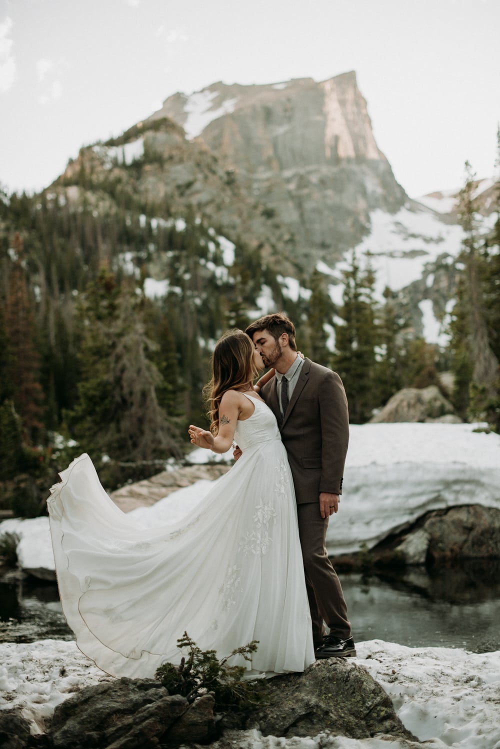 A couple embraces each other after hiking up to Dream Lake in Rocky Mountain national park during their adventure hiking elopement