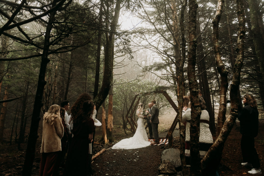 couple at altar at a foggy woodland elopement ceremony with family and friends