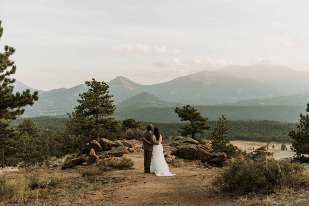 Looking out at Longs Peak and other mountain views in rocky mountain national park, a couple enjoys their adventure elopement