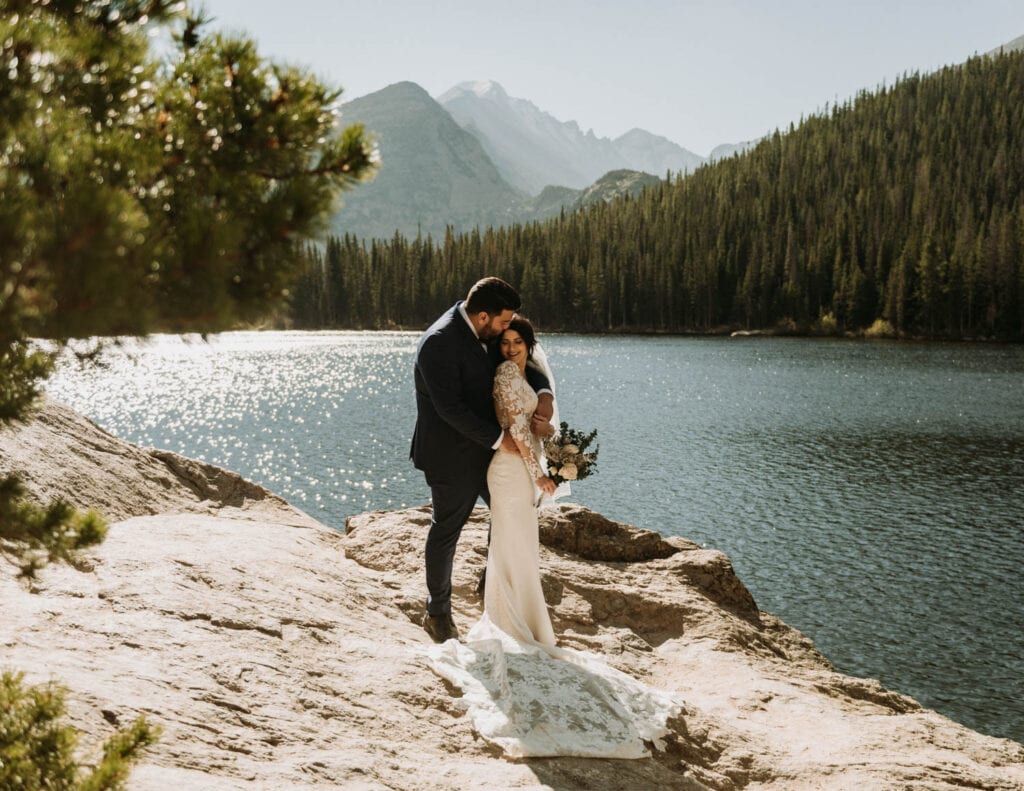 A couple snuggling on a large rock in front of Bear Lake in rocky mountain national park for their elopement