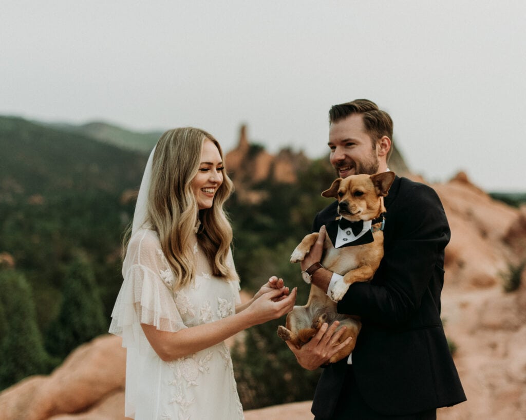 a couple is holding their dog on their elopement day at garden of the gods in Colorado Springs