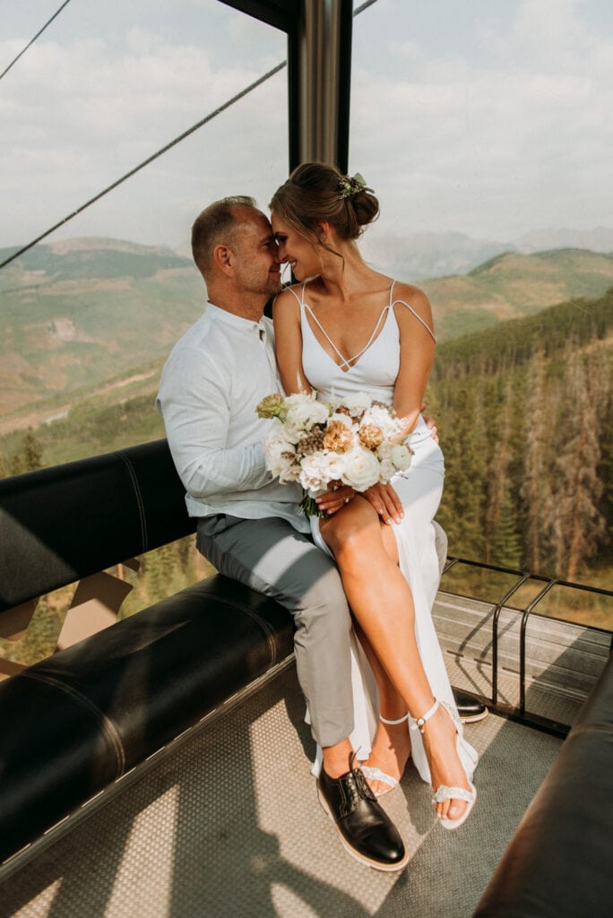 A bride and groom riding the ski lift up to their elopement ceremony location. Elopement ideas for how to incorporate a unique transportation idea.