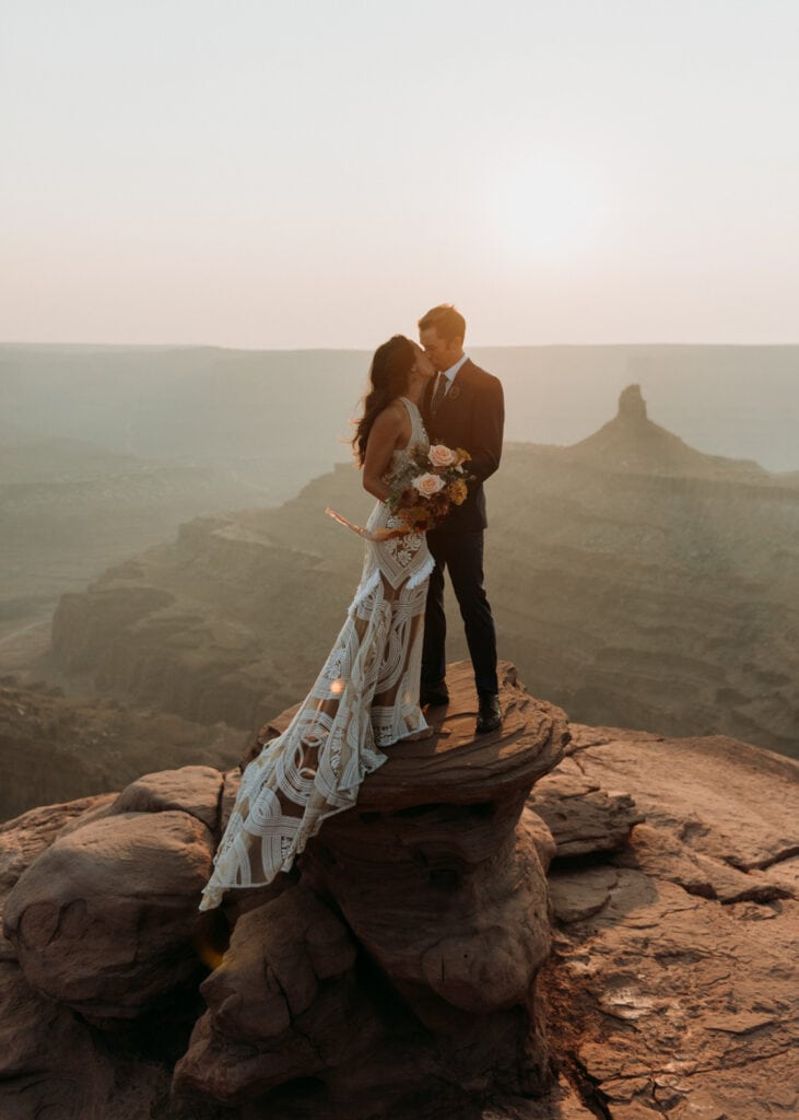 A wedding couple standing on a rock in Dead Horse Point State Park for their moab elopement photographer