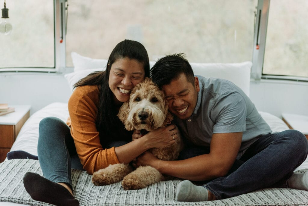 Couple snuggles their dog on a bed in a Renovated airstream at autocamp Yosemite the day before their Yosemite elopement
