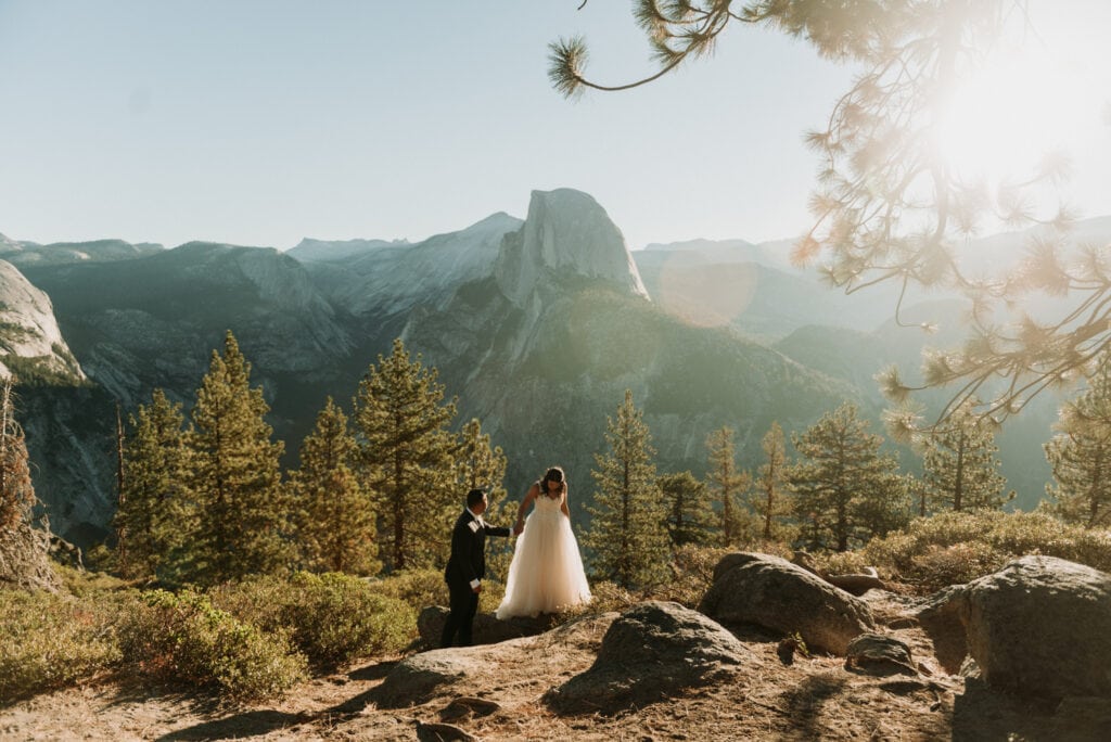 A couple walking around at glacier point in their wedding attire during their elopement at yosemite national park