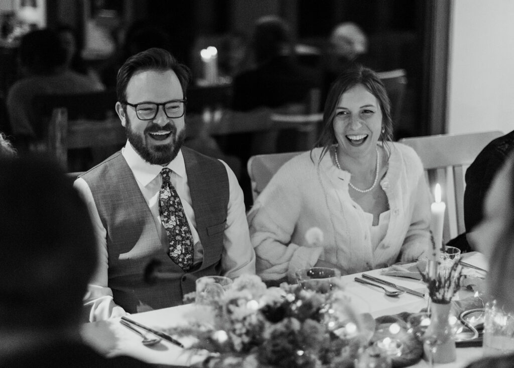 A couple laughing during their intimate dinner after their Airbnb wedding