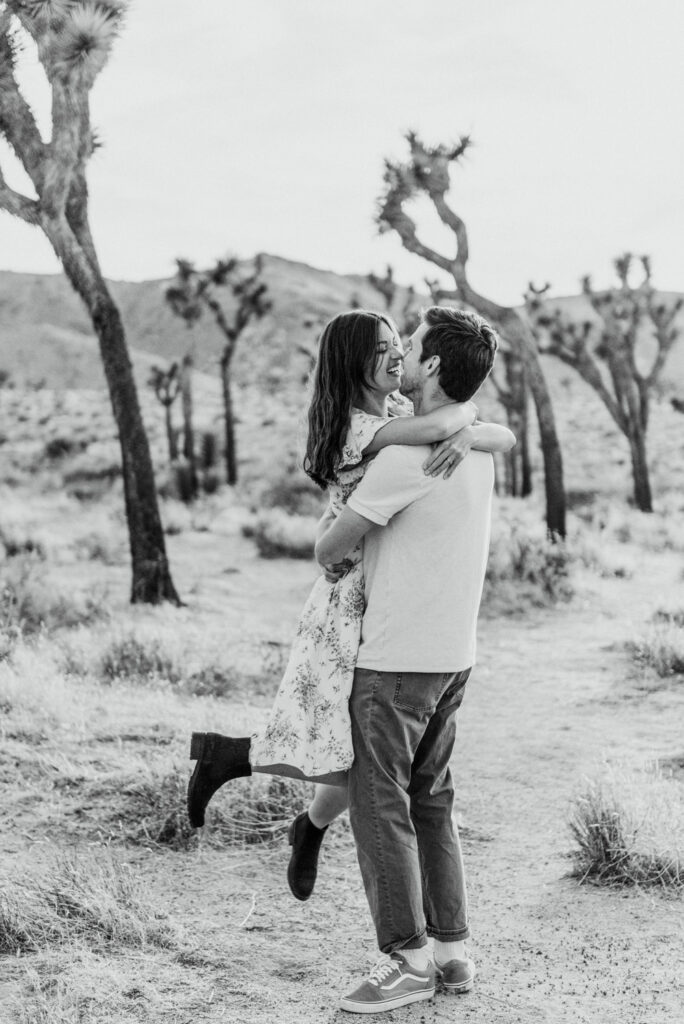 Husband picking up his wife and spinning them in the desert for their anniversary session in Joshua Tree california. Joshua tree national park engagement photos at cap rock