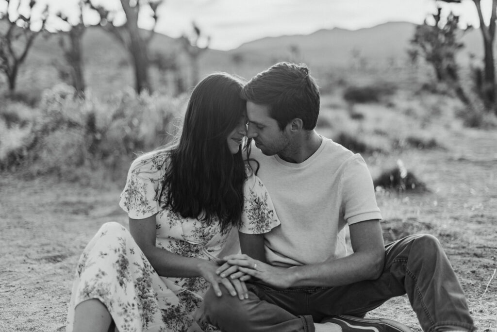 A couple snuggling during their anniversary session in Joshua Tree california. Joshua tree national park engagement photos at cap rock