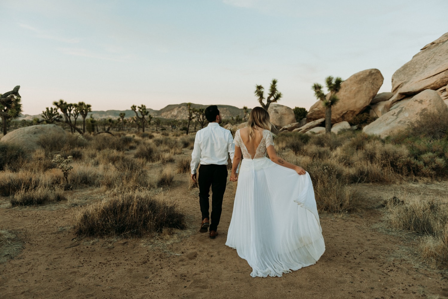 couple walking away during their elopement in joshua tree national park, one of the best places to elope in California