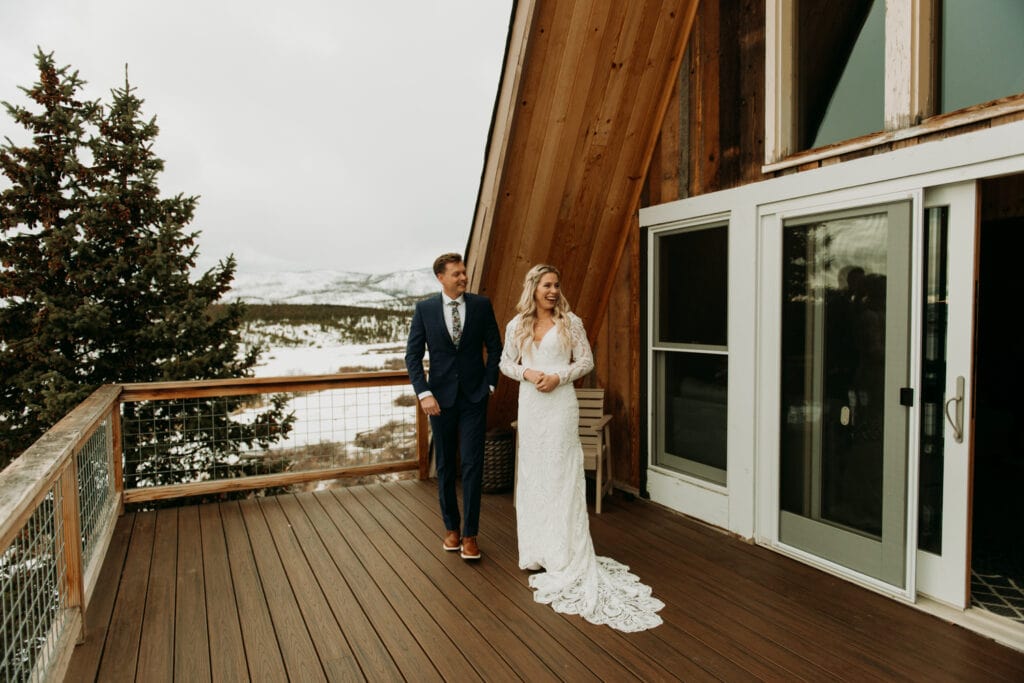 A couple is laughing outside their A frame Airbnb during their winter elopement in Grand Lake Colorado
