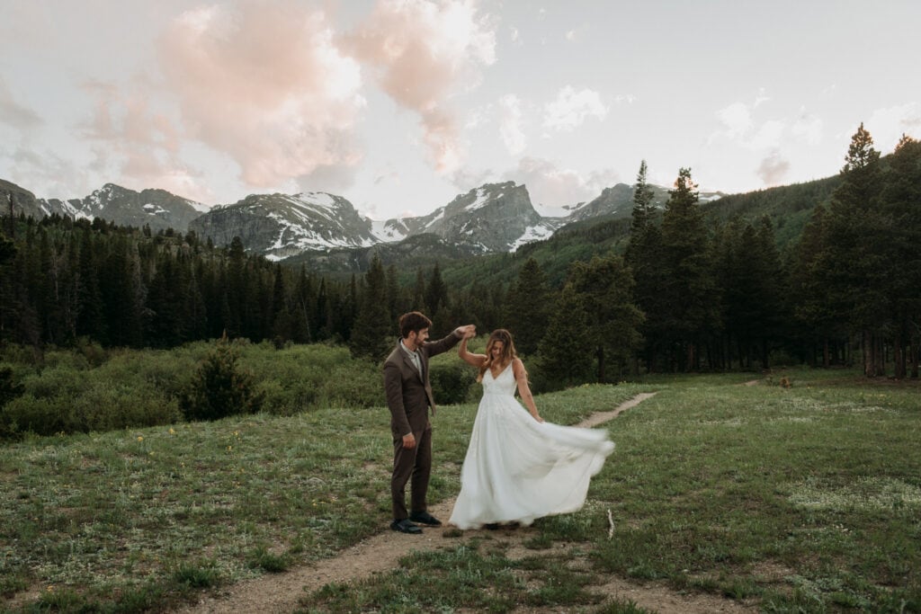 Bride and groom dancing with the Rocky Mountains in the distance in the national park at their micro wedding venue