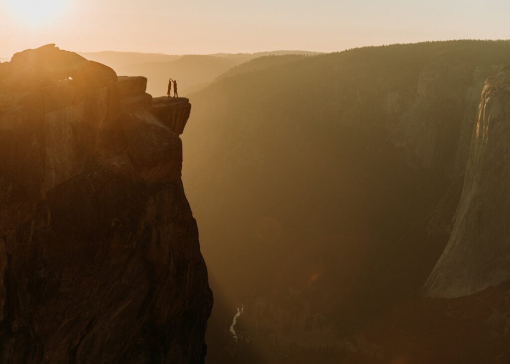 Couple in wedding attire dancing on the edge of a cliff at Taft Point in Yosemite National Park on their elopement day
