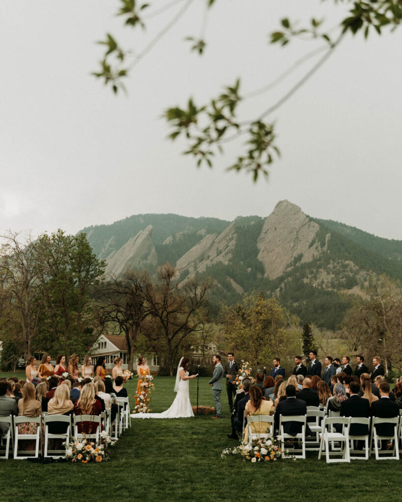 A wedding ceremony takes place beneath the Flatirons in Boulder Colorado at Chautauqua Park, a micro wedding venue in Boulder