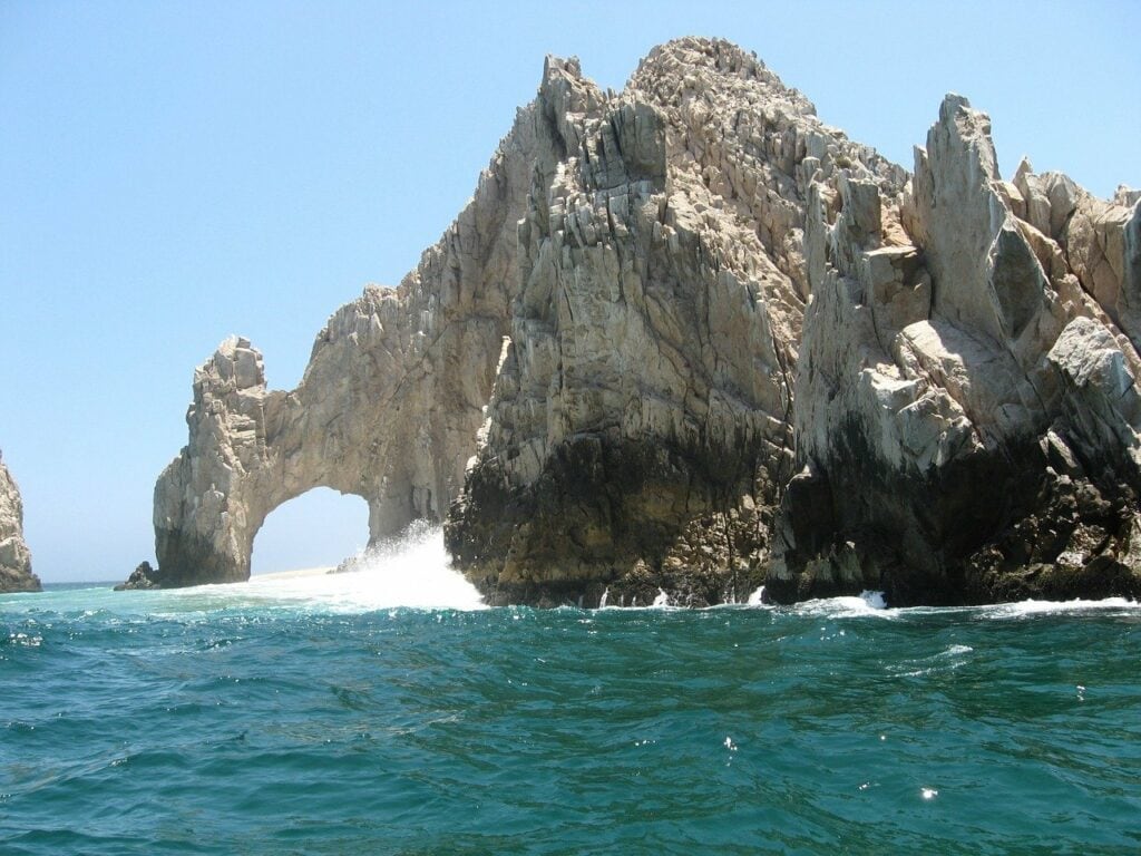 Water splashing against the arch of cabo san lucas, how to elope in mexico
