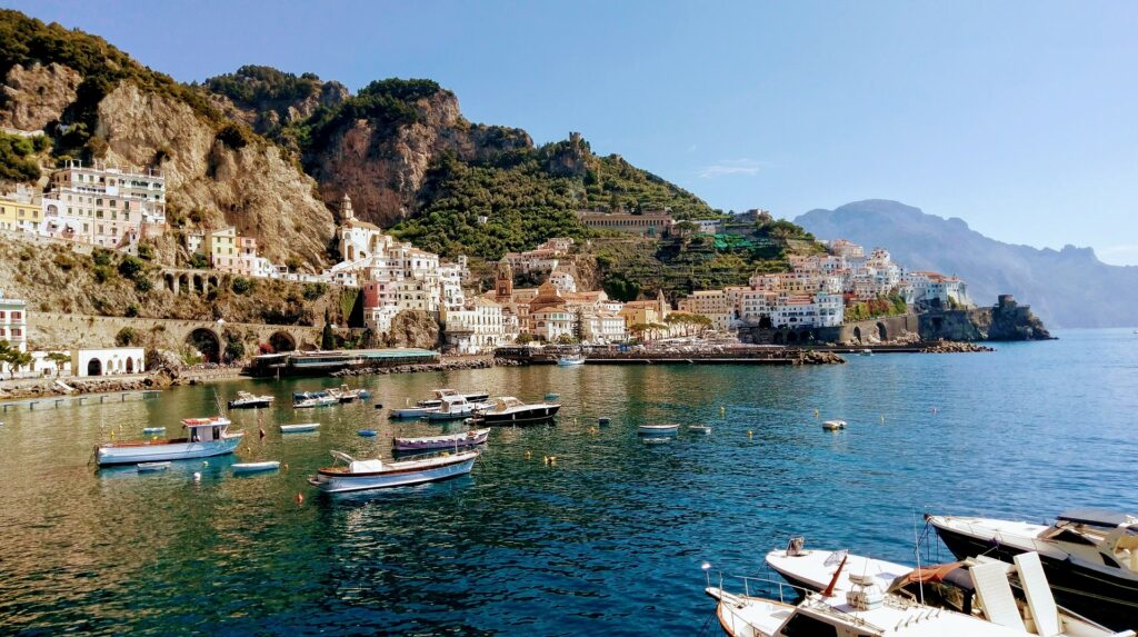A sunny day on the amalfi coast of Italy, boats moored & sailing into the Mediterranean waters along the coast. How to elope Amalfi Coast