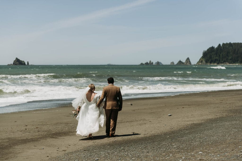 a couple walks down Rialto Beach in Olympic National Park on their elopement day in Washington