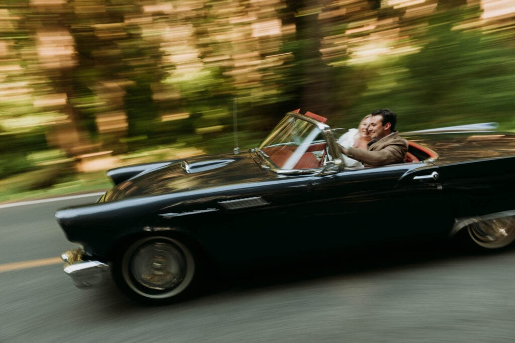 a couple is driving a vintage thunderbird on their elopement day in olympic national park