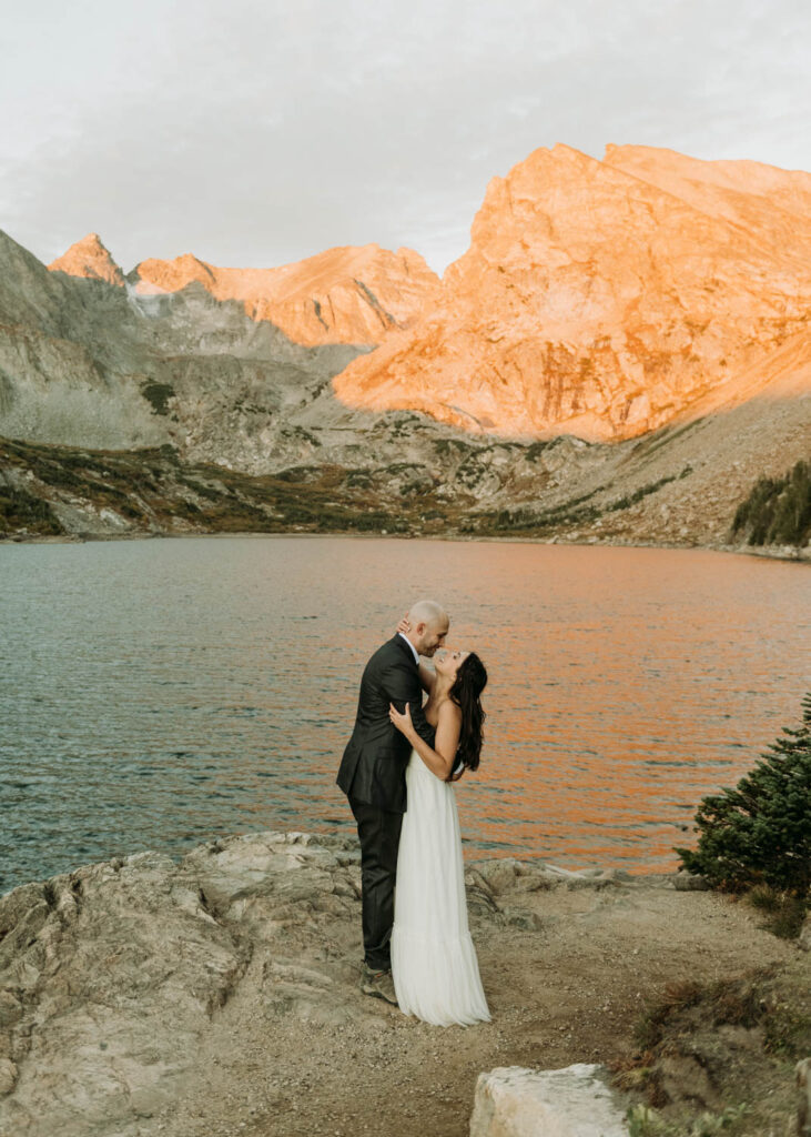 after sharing their vows, a couple embraces at lake isabelle during their elopement