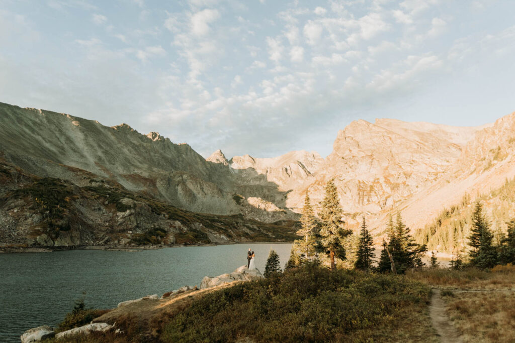 A couple enjoying sunrise at lake isabelle with the jagged peaks in the distance