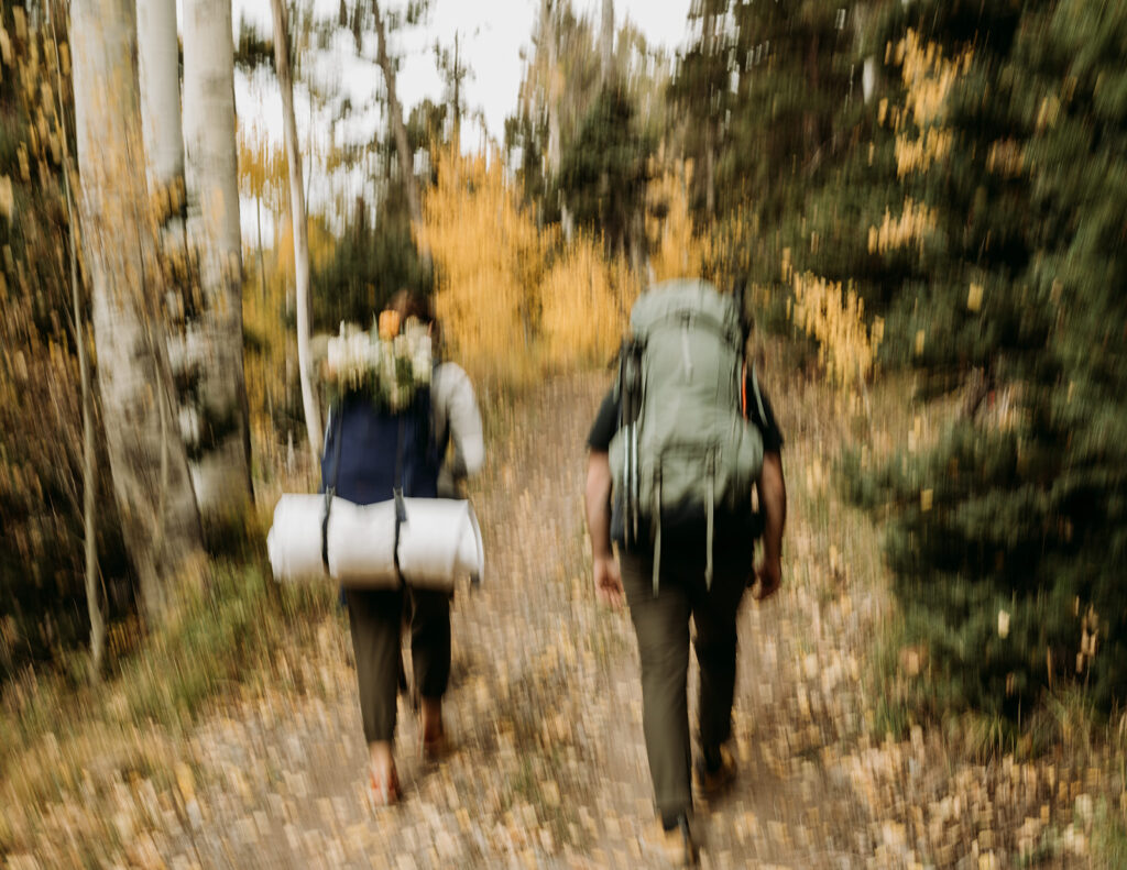 A couple hikes up to their wedding location in the San Juan Mountains for their fall elopement in Colorado