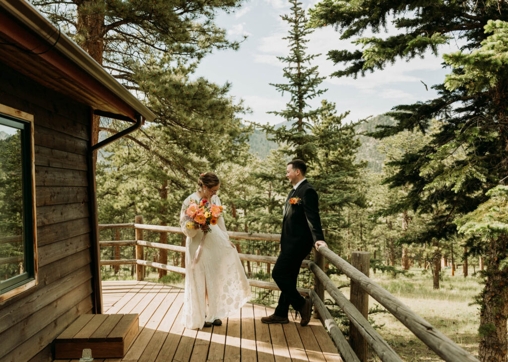 A couple standing on the porch of their cabin while getting ready for their rocky mountain elopement