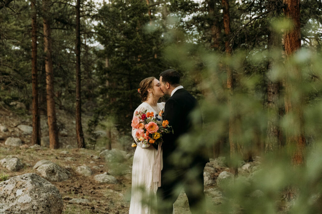 Wedding couple shares a kiss in the forest during their rocky mountain elopement