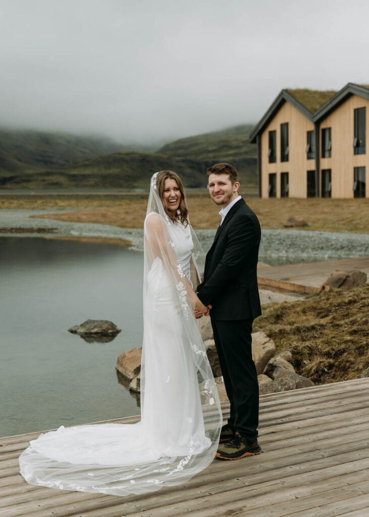 A couple holds hands and laughs while looking at the camera at Hotel Jokulsarlon for their elopement