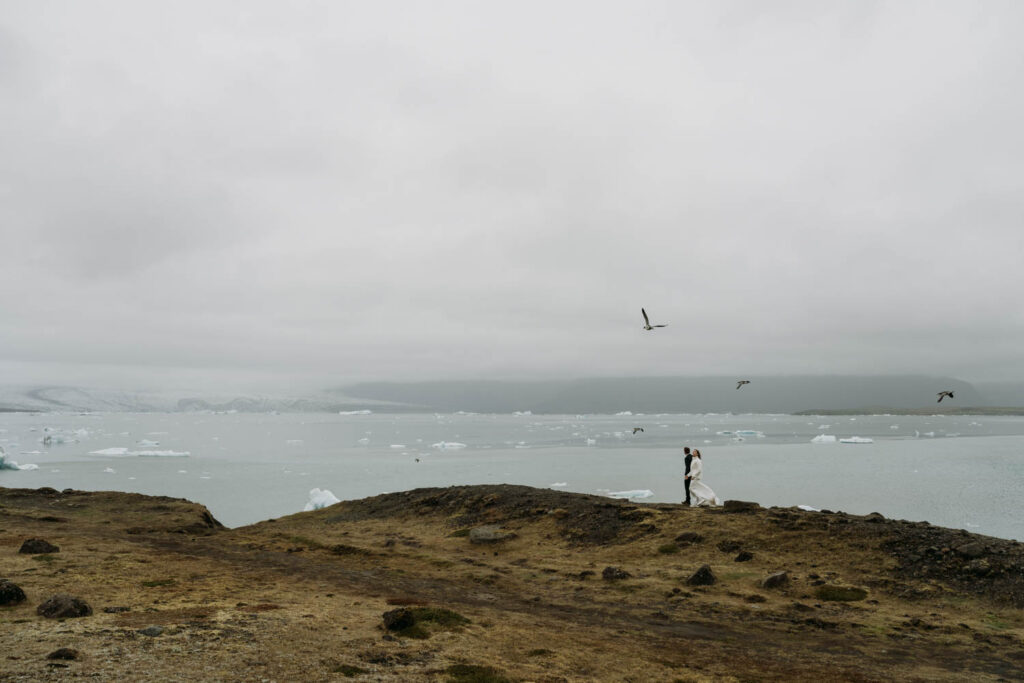 A couple wanders the shoreline of Jokulsarlon Glacier Lagoon in Iceland during their Stokksnes elopement