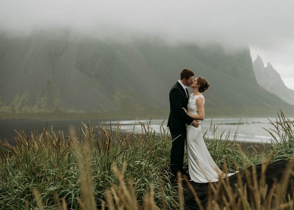 A couple embraces in front of a foggy Vestrahorn during their Stokksnes elopement